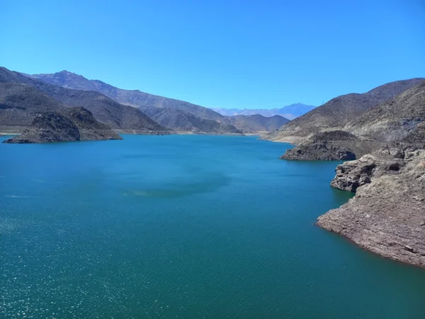 Vista del Embalse Puclaro, un impresionante cuerpo de agua de color azul intenso rodeado por montañas áridas bajo un cielo despejado. El paisaje combina la serenidad del agua con la majestuosidad de las montañas, creando un entorno natural único y espectacular.